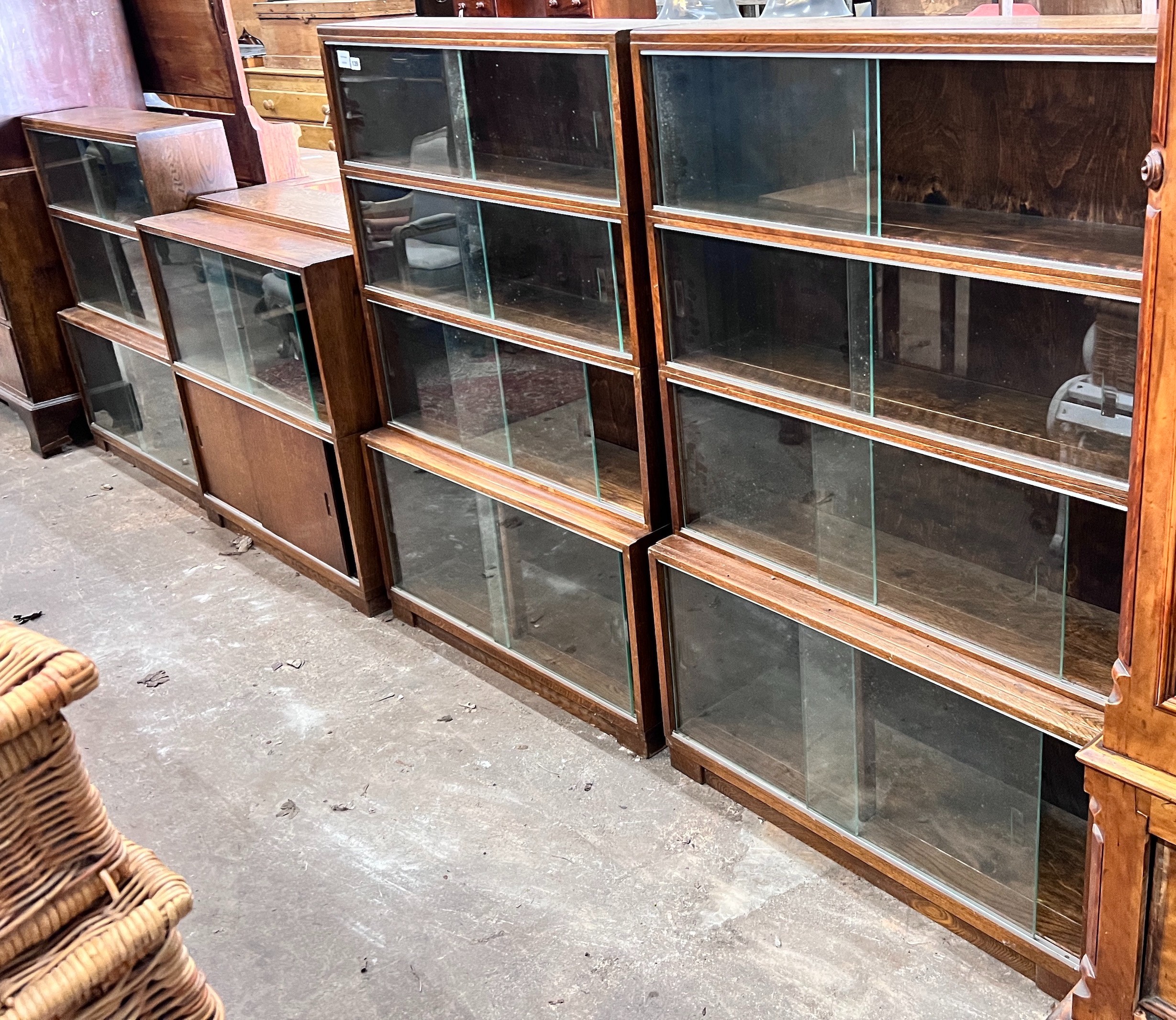 Five 1960's oak Minty bookcases comprising two four section, one three section, and a near pair of two section bookcases, widest 89cm, depth 30cm, height 135cm *Please note the sale commences at 9am.